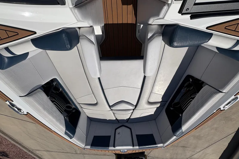 Slide: The Image of 2018 Nautique Super Air Nautique G25 interior with white and blue seating, cup holders, and wood accents. - 9