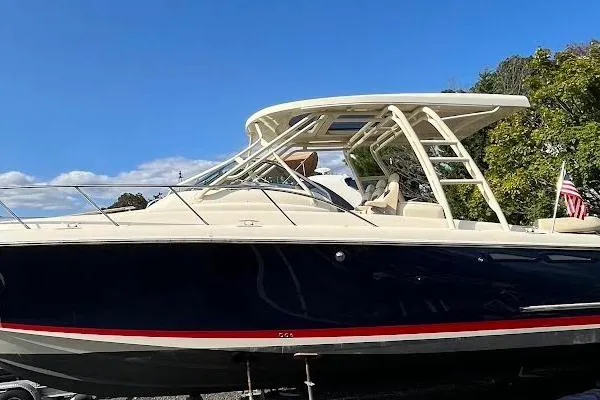 Slide: The Image of 2016 Chris-Craft Launch 36 boat with sleek design and American flag, under clear blue sky. - 1
