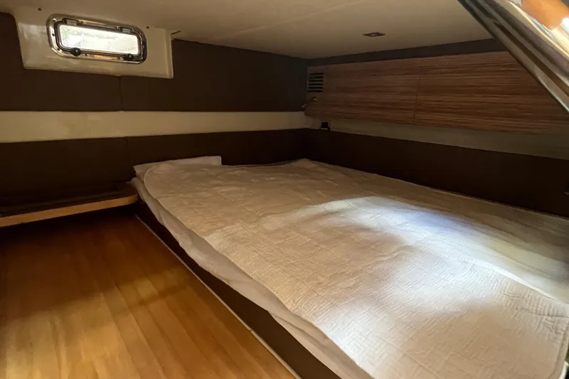Slide: The Image of 2016 Chris-Craft Launch 36 cabin interior with bed, wooden accents, and window. - 23