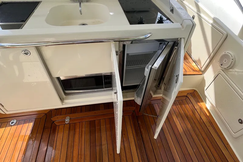 Slide: The Image of 2016 Chris-Craft Launch 36 boat interior with open fridge and sink on teak flooring. - 58