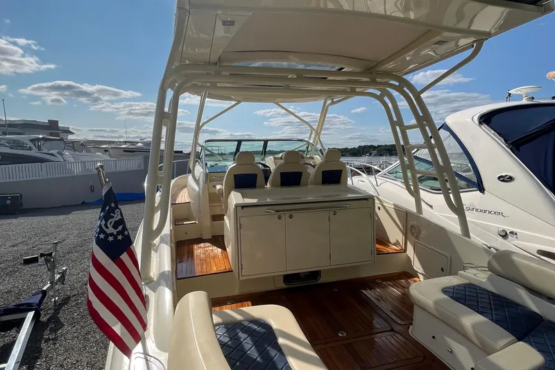 Slide: The Image of 2016 Chris-Craft Launch 36 boat interior with seating and American flag, docked under a sunny sky. - 60