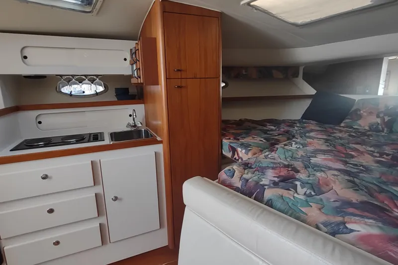 Slide: The Image of Interior of 1996 Tiara Yachts 3100 Open, featuring kitchenette and cozy sleeping area. - 22