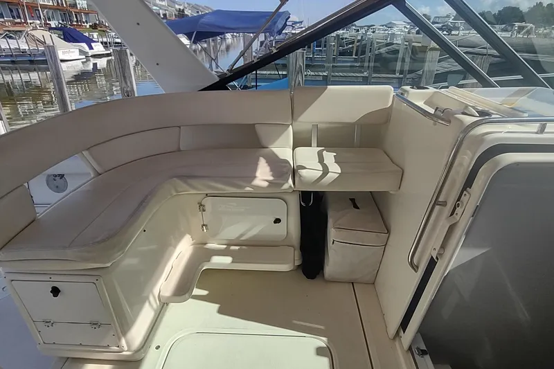 Slide: The Image of 1996 Tiara Yachts 3100 Open interior with cushioned seating and storage, docked at a marina. - 8