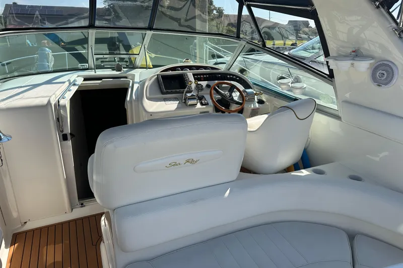 Slide: The Image of 2000 Sea Ray 310 Sundancer cockpit with white seating and wooden steering wheel. - 10