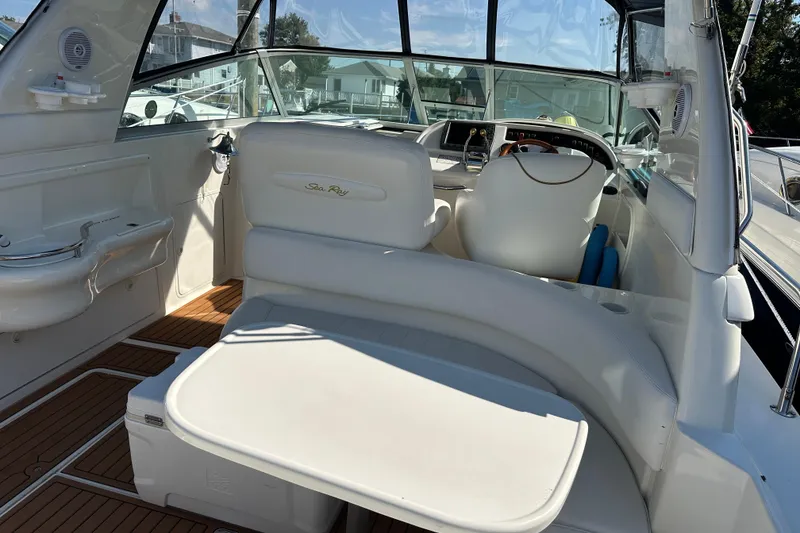Slide: The Image of 2000 Sea Ray 310 Sundancer boat interior with white seating and wooden flooring. - 13