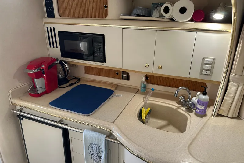 Slide: The Image of Compact kitchen area in a 2000 Sea Ray 310 Sundancer boat with appliances and sink. - 16