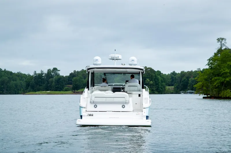 Slide: The Image of 2026 Regal 36 Grande Coupe cruising on a serene lake with lush green surroundings. - 2