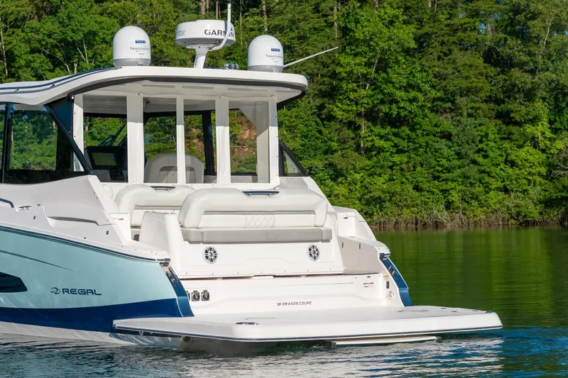 Slide: The Image of 2026 Regal 36 Grande Coupe yacht on a serene lake with lush green forest backdrop. - 3