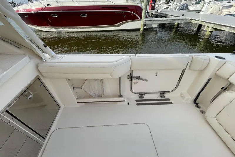 Slide: The Image of 2016 Grady-White Freedom 335 boat interior with white seating and docked red boat nearby. - 42