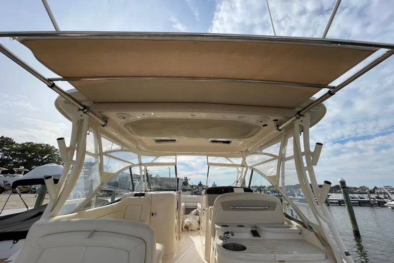 Slide: The Image of 2016 Grady-White Freedom 335 boat interior with canopy, docked at marina under blue sky. - 52