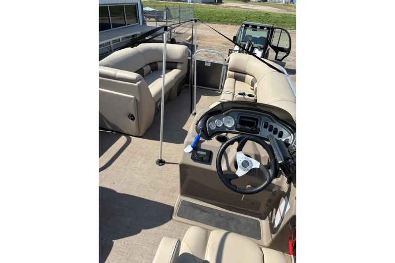 Slide: The Image of 2022 Sun Tracker Party Barge 20 DLX interior with beige seating and steering console. - 10