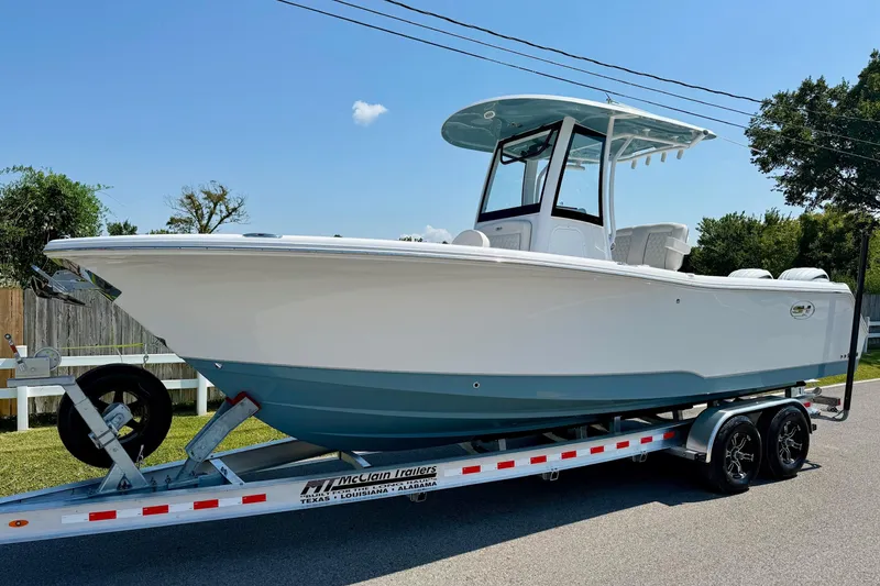 Slide: The Image of 2026 Sea Hunt Gamefish 25 boat on trailer, parked on a sunny street. - 1