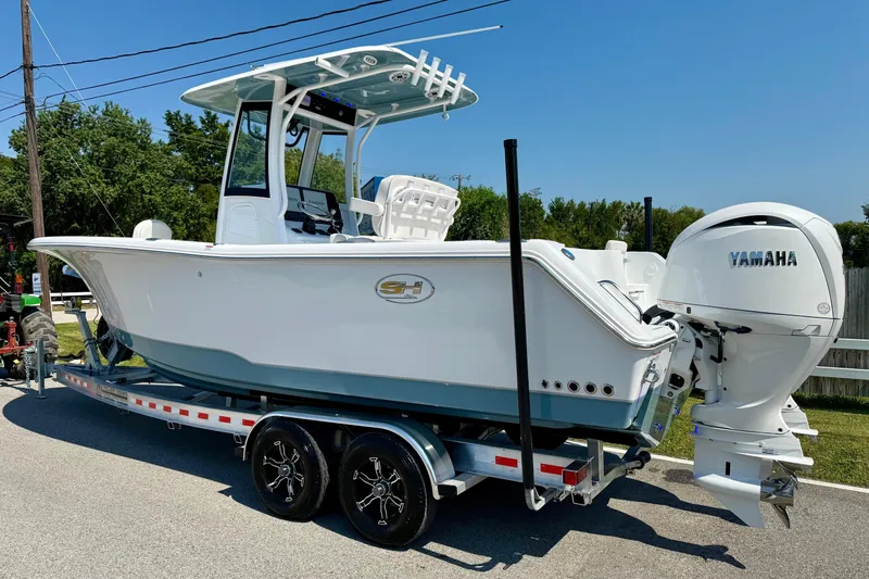 Slide: The Image of 2026 Sea Hunt Gamefish 25 boat on trailer with Yamaha engine, parked outdoors. - 2