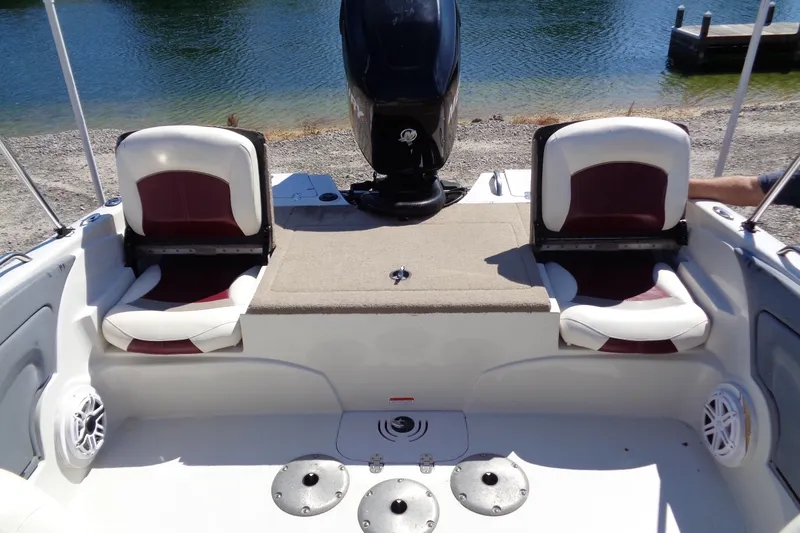 Slide: The Image of 2011 Nitro 290 boat interior with seating and motor, near a lake shore. - 14