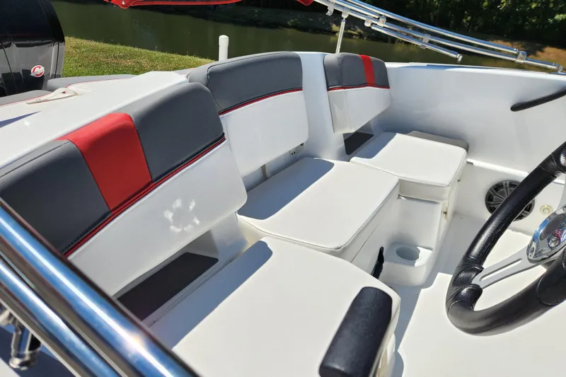 Slide: The Image of 2022 Tahoe T18 boat interior with red and gray seating, steering wheel, and cup holder. - 12