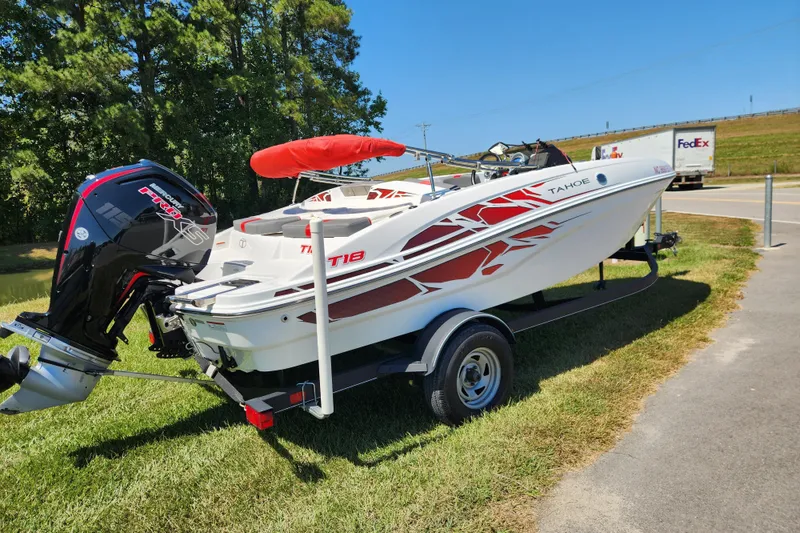 Slide: The Image of 2022 Tahoe T18 boat on trailer with outboard motor, parked on grass under clear sky. - 2