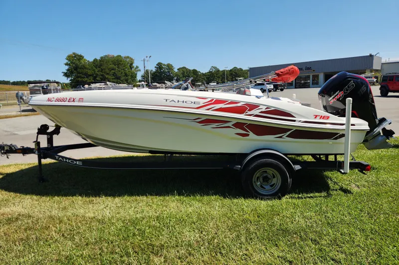 Slide: The Image of 2022 Tahoe T18 boat on trailer, parked on grass, with red and white design. - 6