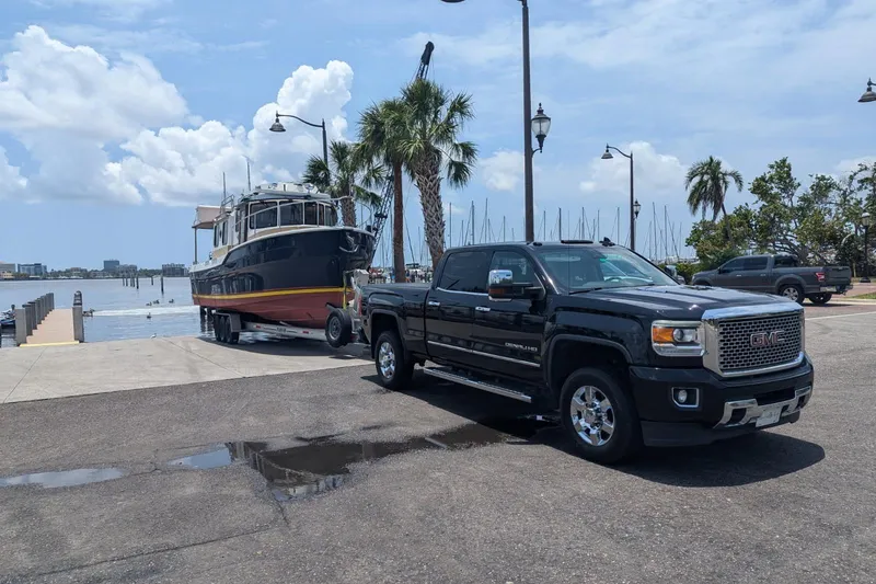 Slide: The Image of GMC truck towing 2014 Ranger Tugs R-31 CB boat at a marina with palm trees. - 2