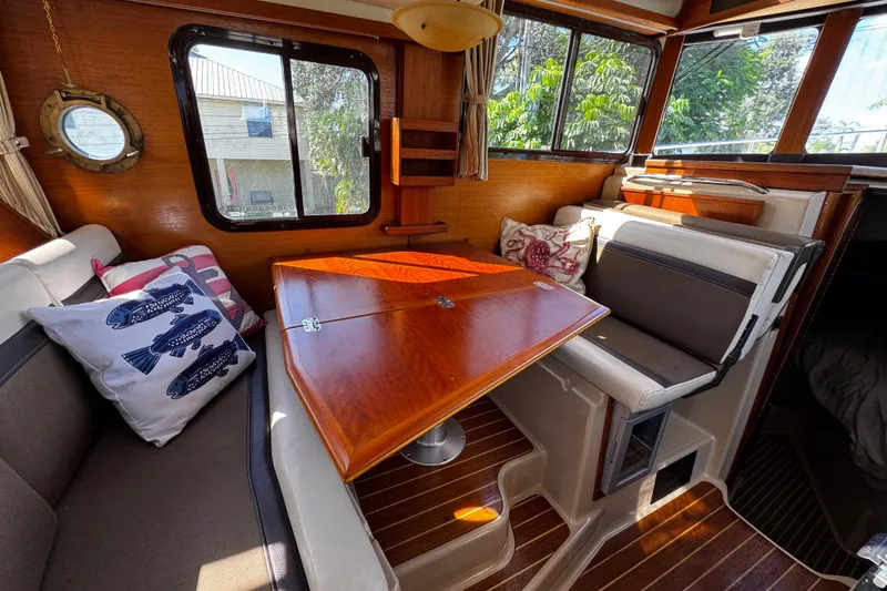 Slide: The Image of 2014 Ranger Tugs R-31 CB interior with wooden table, cushioned seating, and nautical decor. - 5