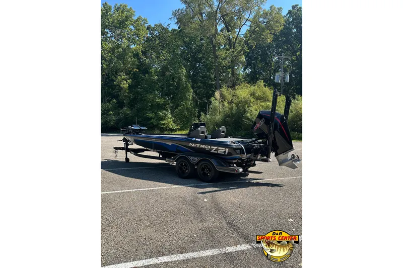 Slide: The Image of 2024 Nitro Z21 XL boat parked in a lot, surrounded by trees. - 3