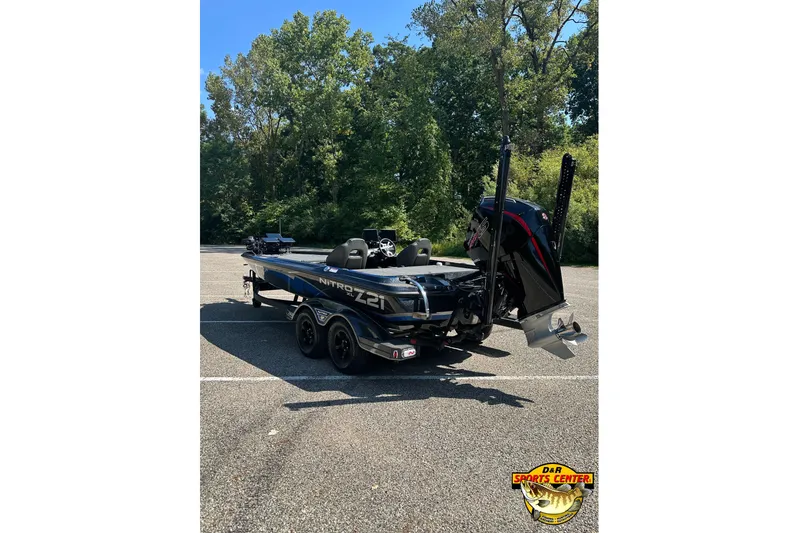 Slide: The Image of 2024 Nitro Z21 XL boat in parking lot, rear view with motor and trees in background. - 5