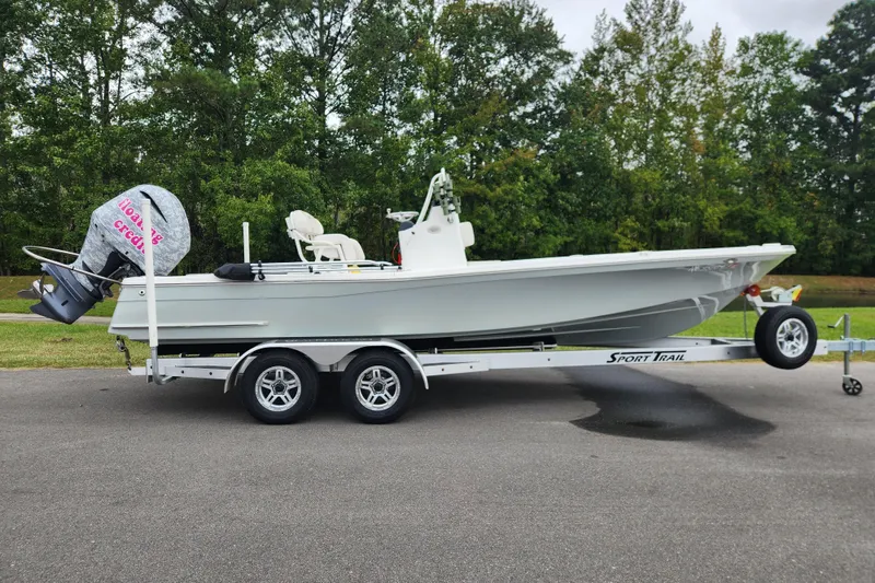The Image of 2019 BlackJack 224 boat on Sport Trail trailer, parked near wooded area. - 0