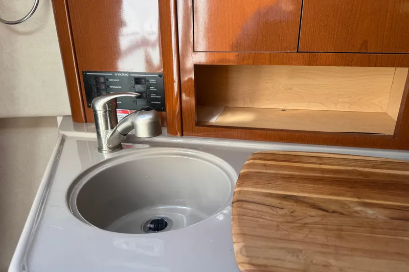 Slide: The Image of 2009 Sea Ray 230 Sundancer galley with sink, faucet, and wooden cutting board. - 6