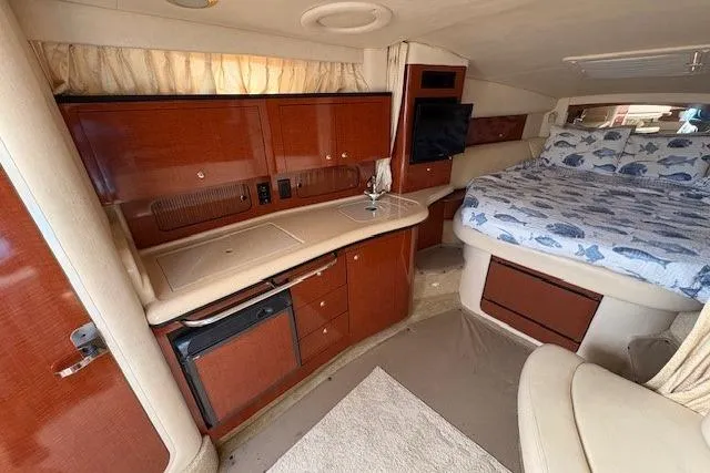 Slide: The Image of 2004 Sea Ray 320 Sundancer cabin interior with bed, kitchenette, and wood cabinetry. - 13