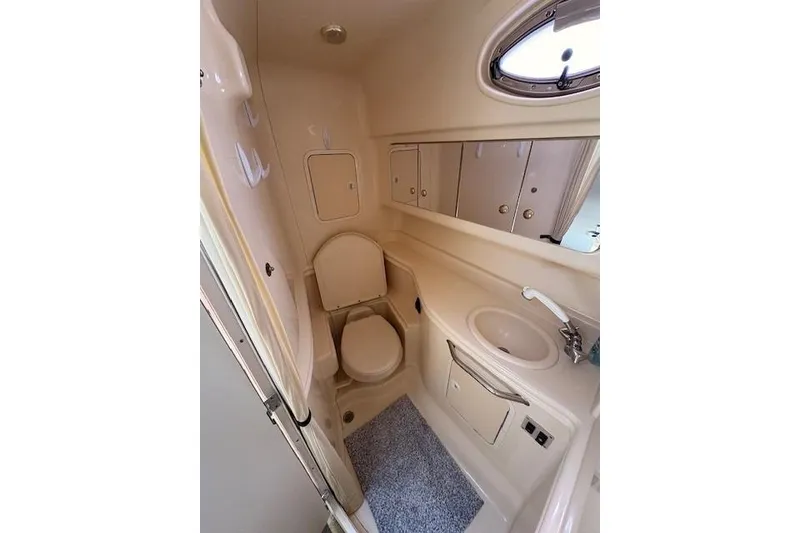 Slide: The Image of 2004 Sea Ray 320 Sundancer bathroom with toilet, sink, mirror, and storage cabinets. - 18