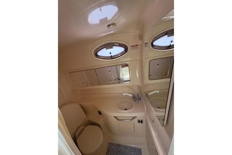 Slide: The Image of 2004 Sea Ray 320 Sundancer bathroom with sink, toilet, and oval windows. - 19