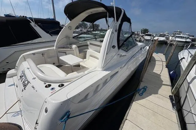 Slide: The Image of 2004 Sea Ray 320 Sundancer docked at marina, featuring sleek design and spacious seating. - 2