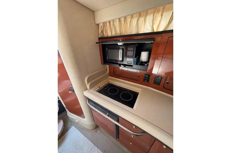 Slide: The Image of 2004 Sea Ray 320 Sundancer kitchen with microwave, stove, and wooden cabinetry. - 20