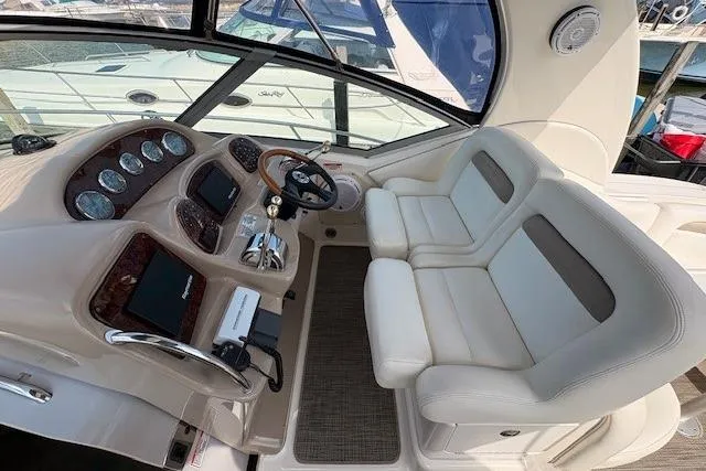 Slide: The Image of 2004 Sea Ray 320 Sundancer helm with dual seats and modern dashboard controls. - 7