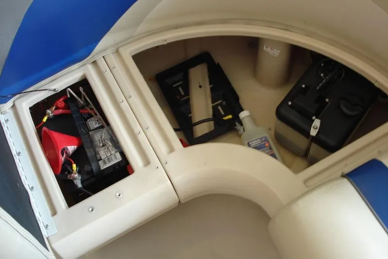 Slide: The Image of 2013 Manitou Aurora 22 VP boat storage compartments with battery and maintenance supplies. - 7