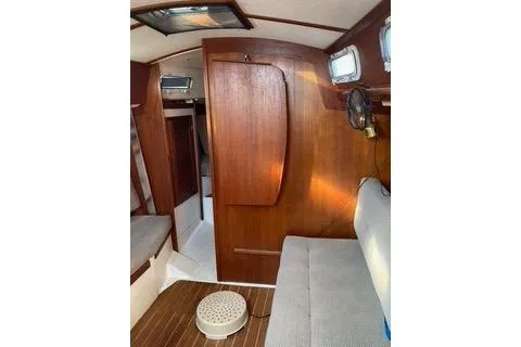 Slide: The Image of Interior of a 1985 Tartan 28 Piper sailboat with wooden paneling and seating. - 12
