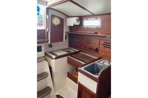 Slide: The Image of 1985 Tartan 28 Piper yacht interior with wooden cabinetry and compact kitchen area. - 7