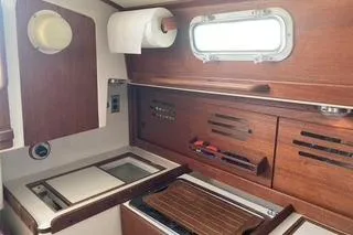 Slide: The Image of 1985 Tartan 28 Piper yacht interior with wooden cabinetry and compact kitchen area. - 8