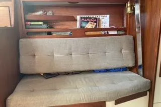 Slide: The Image of 1985 Tartan 28 Piper interior with cushioned seating and wooden shelving. - 9