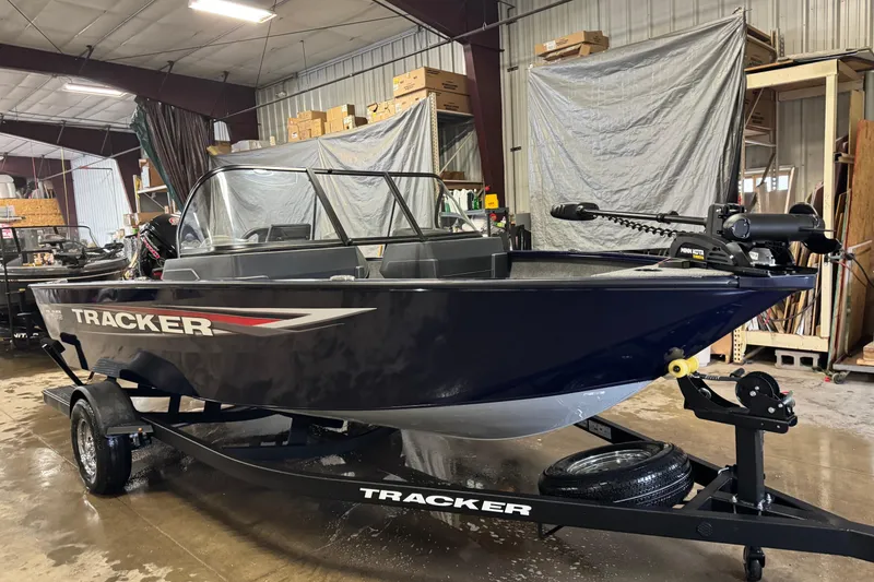 Slide: The Image of 2025 Tracker Pro Guide V-175 Combo boat in showroom, on trailer, with modern design. - 2