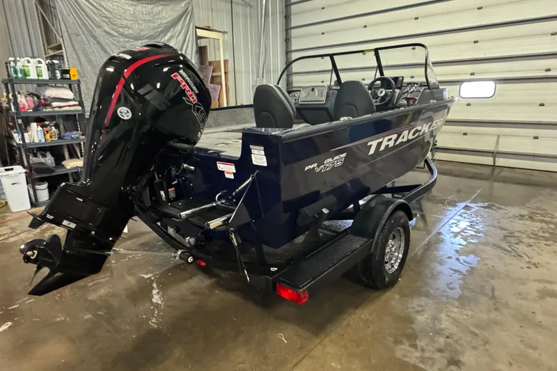 Slide: The Image of 2025 Tracker Pro Guide V-175 Combo boat in a garage, showcasing its powerful outboard motor. - 3