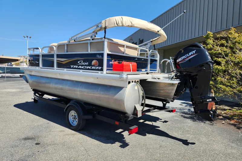 Slide: The Image of 2023 Sun Tracker Bass Buggy 16 XL Select pontoon boat with Mercury engine on trailer. - 2
