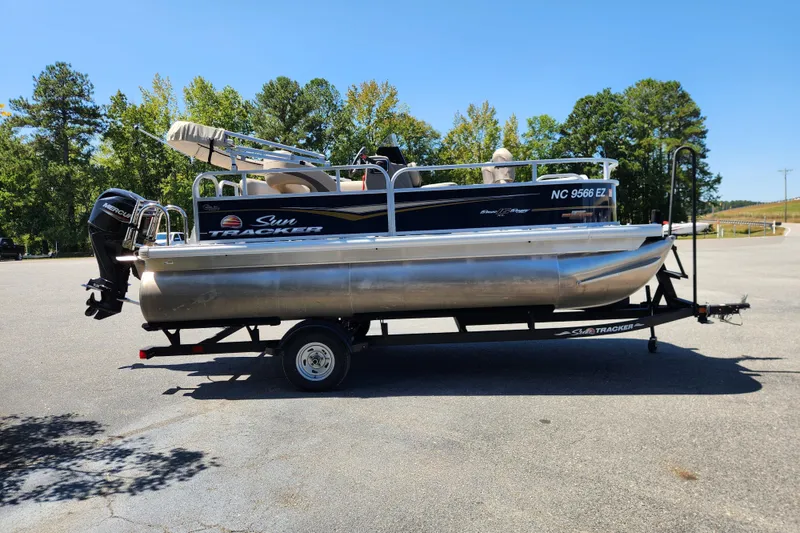 Slide: The Image of 2023 Sun Tracker Bass Buggy 16 XL Select pontoon boat on trailer in parking lot. - 4