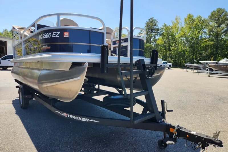 Slide: The Image of 2023 Sun Tracker Bass Buggy 16 XL Select pontoon boat on trailer in sunny outdoor setting. - 6