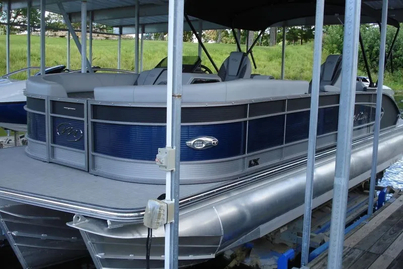 Slide: The Image of 2024 Manitou LX 25 Rear Facing X-Treme pontoon boat docked under a canopy. - 6