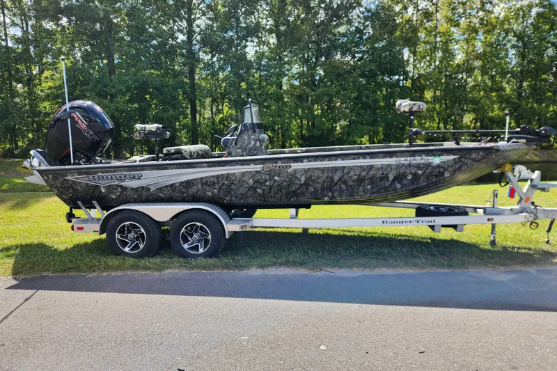 Slide: The Image of 2024 Ranger RB200 boat on trailer, parked on grass with forest background. - 0