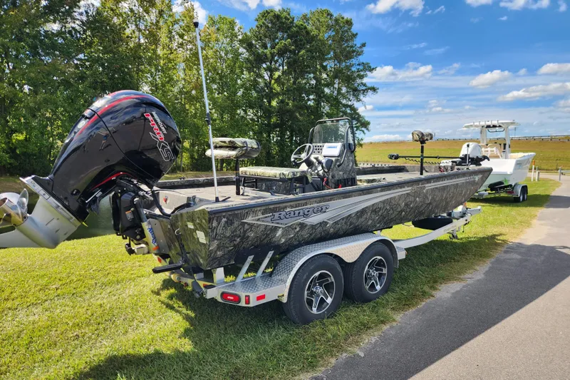 Slide: The Image of 2024 Ranger RB200 boat on trailer, featuring powerful outboard motor, parked on grass. - 2