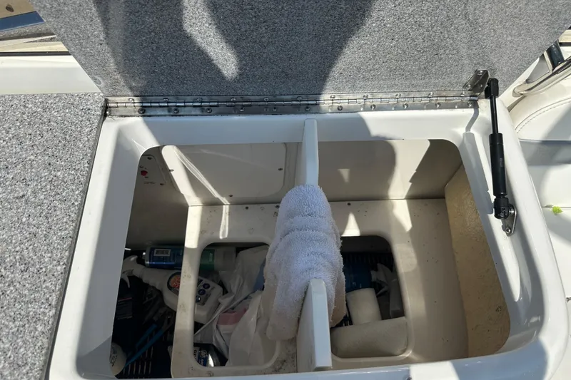 Slide: The Image of Open storage compartment on a 2005 Formula 260 Bowrider boat, containing various items. - 13