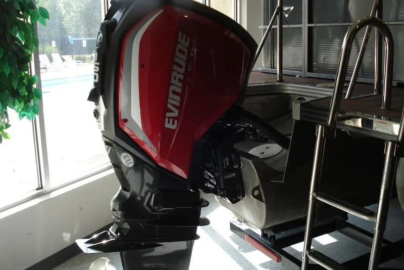 Slide: The Image of 2016 Manitou 23 VP Aurora with Evinrude outboard motor, displayed indoors near a pool. - 7