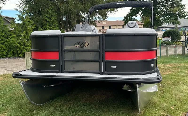 Slide: The Image of 2025 Bentley Pontoons Legacy 220 Navigator on grass, featuring sleek black and red design. - 2