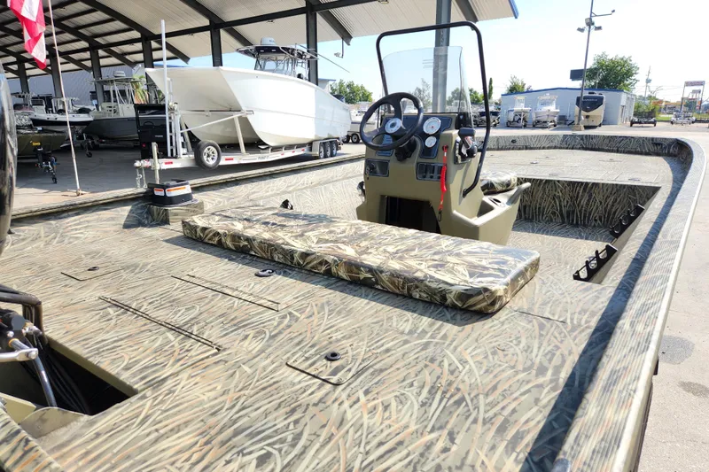 Slide: The Image of 2025 Tracker Grizzly 2072 CC boat with camouflage design, parked outdoors under a canopy. - 9